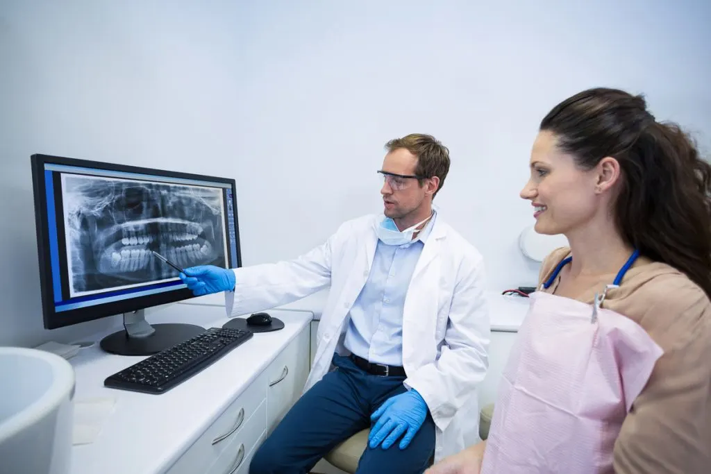 En kvinna hos tandläkaren får en röntgenbild av en tandprotes förklarad