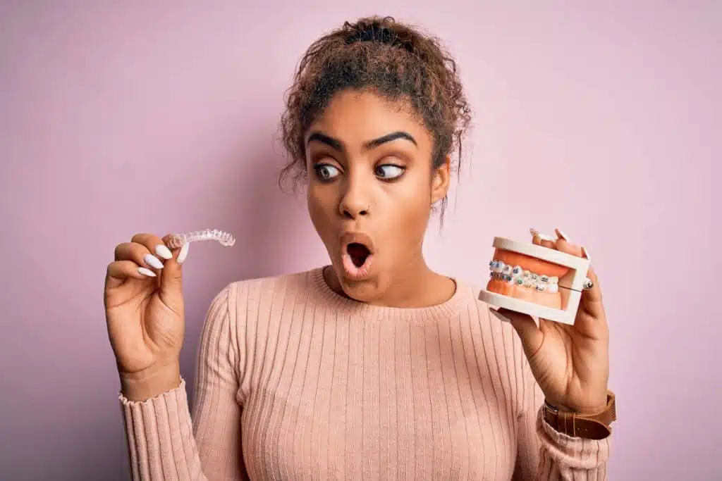 Overbite: What is it actually and how does the treatment proceed? 5 Woman compares aligner with fixed braces