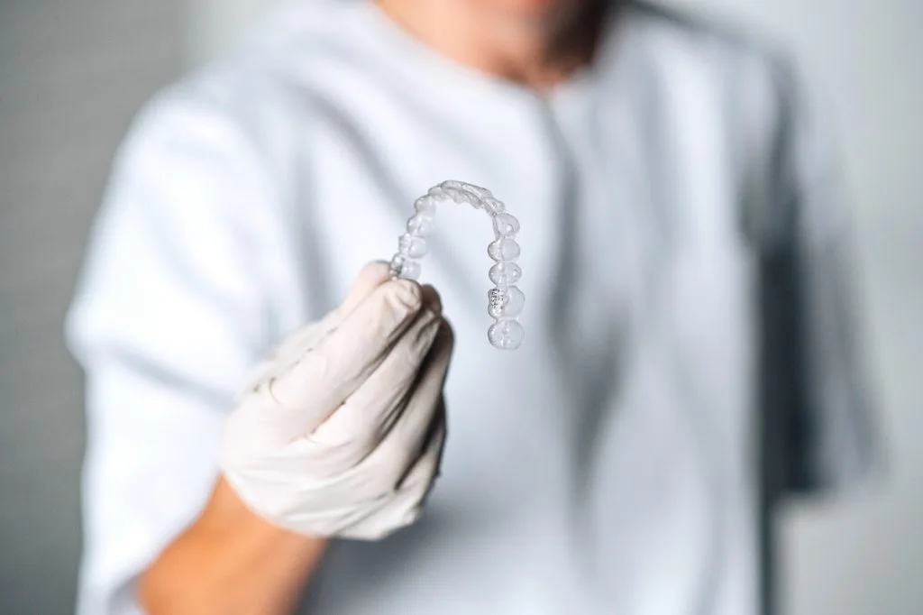 Un dentista sostiene una férula dental invisible en la mano
