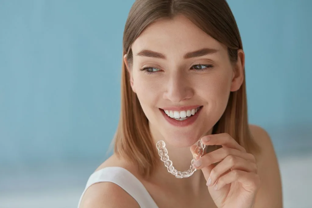 Woman holding aligner in hand with smile  