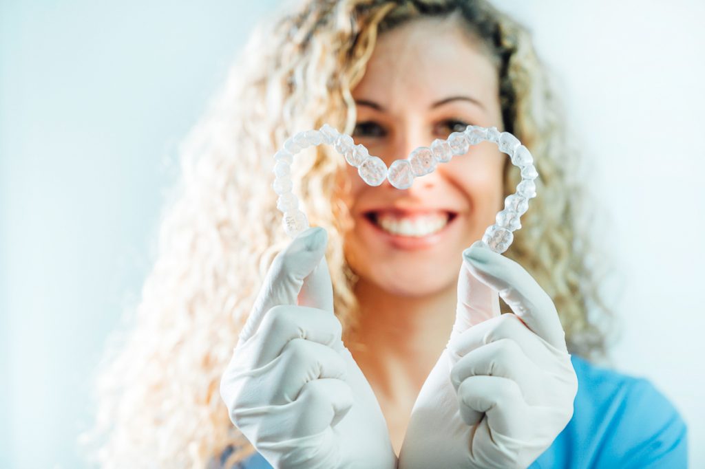 PlusDental experience: Dentist holds aligner upwards