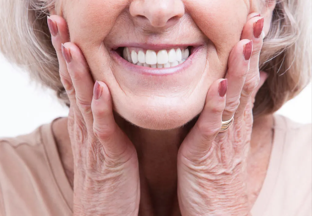 Mujer mayor sonríe a la cámara - PlusDental costes