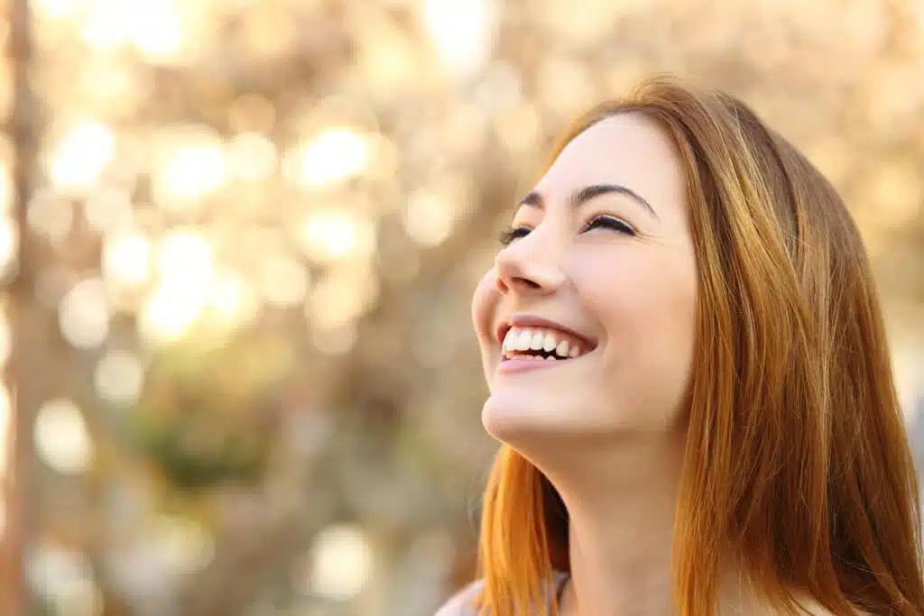 Young woman laughing radiantly into the camera - DrSmile Berlin