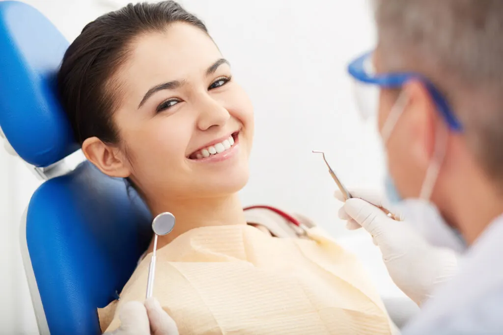 Jonge vrouw liggend in de tandartsstoel in een goed humeur
