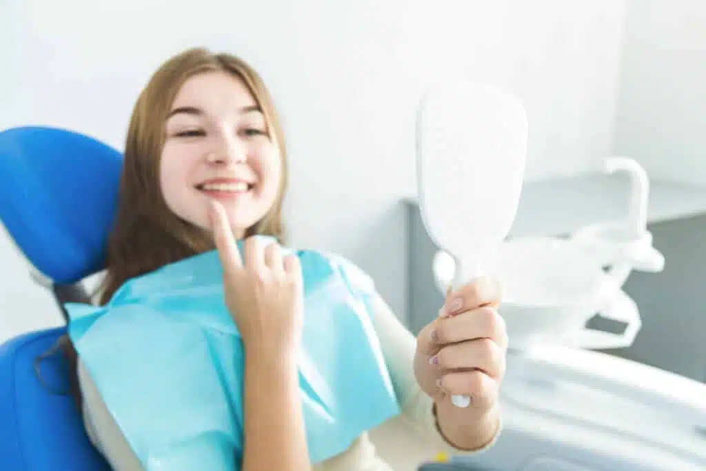 Morsure de couverture : qu'est-ce que cela signifie et comment peut-on la traiter ? 5 Jeune femme souriante chez le dentiste