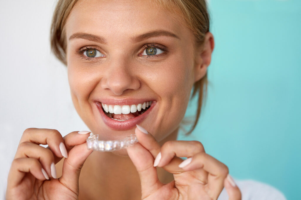Women smiling with Aligner in hands - Can I Wear My Retainer After Wisdom Teeth Removal?