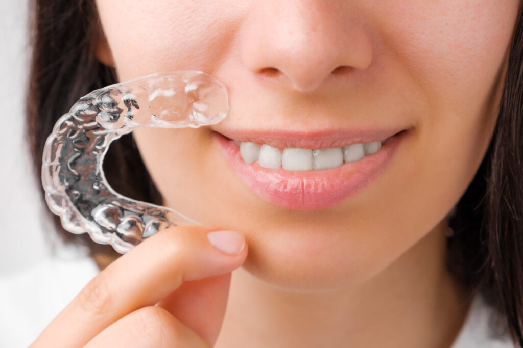 Young woman holding aligner in hand - closeup